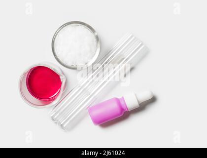 Reagenzglas und Serumflasche mit Tropf neben Kaliumpermanganatflüssigkeit im Becher und mikrokristallinem Wachs in Glasbehälter. Chemikalien Stockfoto