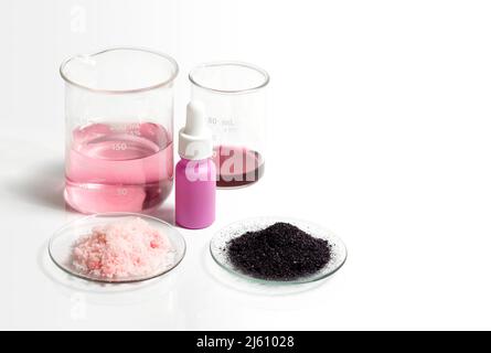 Kaliumpermanganat Flüssigkeit, Serumflasche mit Tropf, KMnO4 und rosa Flockenchemikalien in chemischem Uhrglas. Kosmetische Chemikalien Inhaltsstoff auf whi Stockfoto