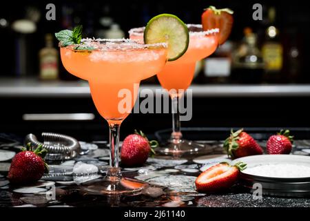 Zwei Erdbeermargaritas auf einer Bar, vor dunklem Hintergrund. Stockfoto