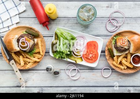 Sliders und Pommes frites auf Holzteller mit einer Platte von Belägen in der Mitte. Stockfoto