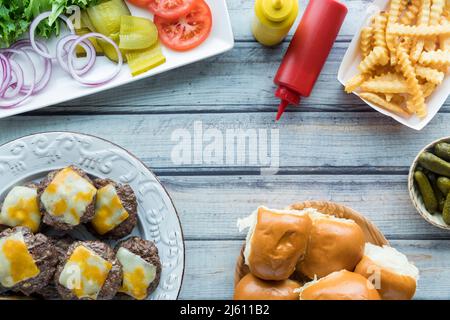 Frisch gegrillte Rindfleischschieber mit Brötchen, Toppings und pommes frites. Stockfoto