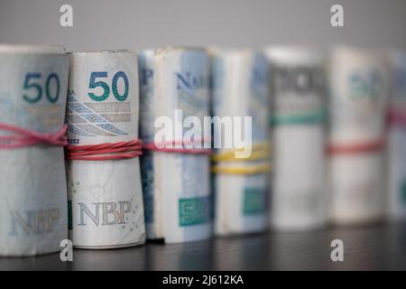 Die Geldscheine rollten und Band zusammen mit einem Gummiband stehen auf der Tischplatte. Stockfoto