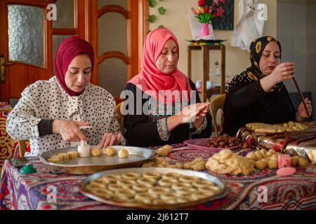 Gaza, Palästina. 26. April 2022. Eine palästinensische Familie stellt in ihrem Haus im zentralen Gazastreifen traditionelle Süßigkeiten her. Muslime auf der ganzen Welt bereiten sich darauf vor, den seligen Eid Al-Fitr zu feiern, der mit dem Ende des heiligen Monats Ramadan zusammenfällt. Kredit: SOPA Images Limited/Alamy Live Nachrichten Stockfoto