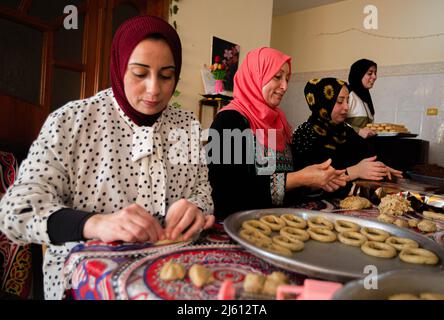 Gaza, Palästina. 26. April 2022. Eine palästinensische Familie stellt in ihrem Haus im zentralen Gazastreifen traditionelle Süßigkeiten her. Muslime auf der ganzen Welt bereiten sich darauf vor, den seligen Eid Al-Fitr zu feiern, der mit dem Ende des heiligen Monats Ramadan zusammenfällt. Kredit: SOPA Images Limited/Alamy Live Nachrichten Stockfoto