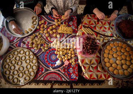 Gaza, Palästina. 26. April 2022. Eine palästinensische Familie stellt in ihrem Haus im zentralen Gazastreifen traditionelle Süßigkeiten her. Muslime auf der ganzen Welt bereiten sich darauf vor, den seligen Eid Al-Fitr zu feiern, der mit dem Ende des heiligen Monats Ramadan zusammenfällt. Kredit: SOPA Images Limited/Alamy Live Nachrichten Stockfoto