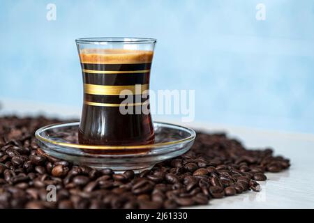 Duftender starker Kaffee und Kaffeebohnen auf blauem Hintergrund. Das Konzept der Heißgetränke. Kopieren Sie Platz für Ihren Text Stockfoto