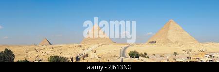 Ein beeindruckender Panoramablick über die gesamte Wüste und alle drei Großen Pyramiden in Gizeh, Ägypten, an einem Tag mit blauem Himmel. Horizontaler Kopierbereich Stockfoto