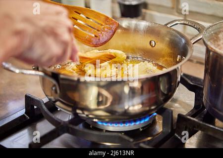 Kochen von Apfelpfannkuchen. Der Küchenchef dreht den Apfeldonut in das kochenden Öl Stockfoto