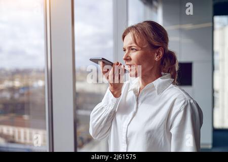 Office Business Concept.Portrait von schönen reifen Frau mit Handy-Aufnahme Voice-Massage Stockfoto
