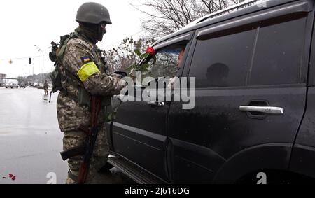 BROVARY, UKRAINE 08. März. Ein Mitglied des ukrainischen Militärs übergibt einem Fahrer zum Internationalen Frauentag an einem Kontrollpunkt in der Nähe der Stadt Brovary außerhalb von Kiew, während der russischen Invasion der Ukraine am 08. März 2022 in Brovary, Ukraine, eine rote Rosenblume. Russland begann eine militärische Invasion der Ukraine, nachdem das russische parlament Verträge mit zwei abtrünnigen Regionen in der Ostukraine gebilligt hatte. Es ist der größte militärische Konflikt in Europa seit dem Zweiten Weltkrieg Stockfoto