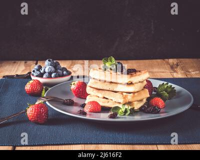 Vollkorn-belgische Waffel mit Minze und frisch gehackten Erdbeeren und Heidelbeeren vor rustikalem Hintergrund mit Wodden-Tisch Stockfoto