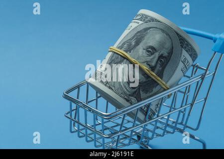 In einen Schlauch gerollte Dollars liegen in einem Einkaufskorb. Stockfoto