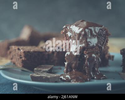 Das Bild zeigt einen Stapel Brownies, der mit Schokoladensauce und einigen Teilen der Tafel verziert ist Stockfoto