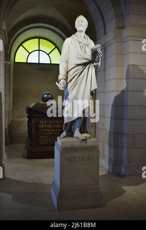 Grab des französischen Schriftstellers und Philosophen der Aufklärung Voltaire in der Krypta des Panthéon in Paris, Frankreich. Vor dem Grab befindet sich die Marmorstatue des stehenden Voltaire des französischen neoklassizistischen Bildhauers Jean-Antoine Houdon (1808-1812). Stockfoto