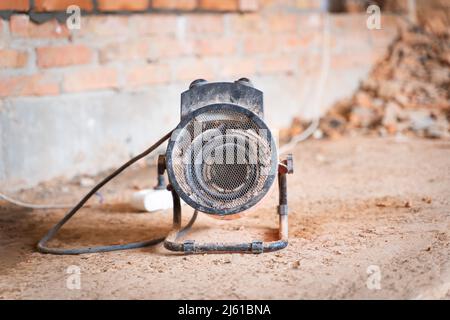 Industrielle Heißluftpistole auf einer Baustelle aus nächster Nähe. Industrielle elektrische Heizung für Heizung und Trocknung von Gebäuden Stockfoto