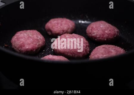 Rinderburger-Patties, die auf einer heißen Pfanne brutzeln. Stockfoto