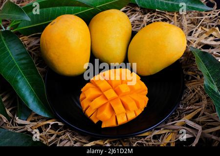 Tropische Mango-Frucht mit grünem Blatt, reife Mango im Gras aus der Nähe Stockfoto