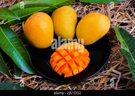 Tropische Mango-Frucht mit grünem Blatt, reife Mango im Gras aus der Nähe Stockfoto