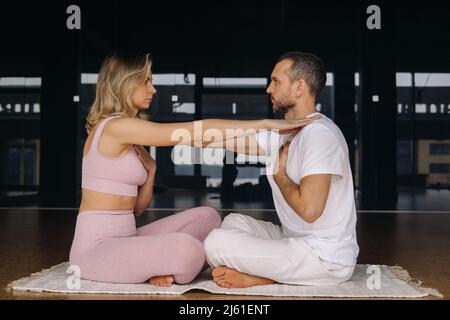 Eine Frau und ein Mann üben im Fitnessstudio Yoga-Paarturnen aus. Stockfoto