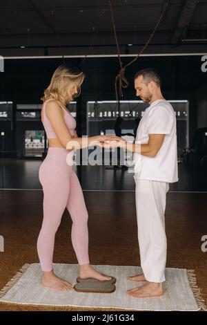 Ein Mann und eine Frau machen Yoga auf Brettern mit Nägeln im Fitnessstudio. Stockfoto