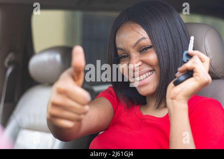die afrikanische Dame mit dem Schlüssel hält Daumen nach oben Stockfoto
