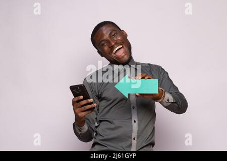 Aufgeregter afrikanischer Mann mit Pfeil zum Telefon zeigend Stockfoto