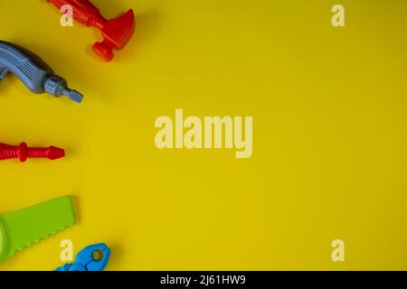 Gelber Hintergrund mit Reparaturspielzeug und Kopierraum, Kinderspiel isoliert auf gelbem Hintergrund, Spielidee, Draufsicht Stockfoto