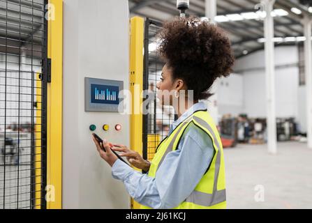 Techniker, der das Sicherheitssystem im Werk über einen Tablet-PC entriegelt Stockfoto