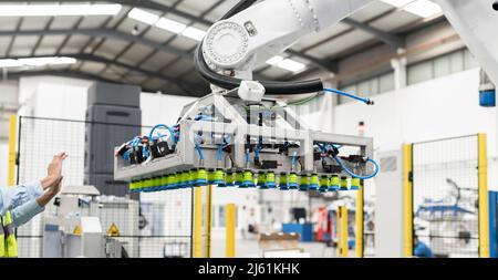 Hand des Ingenieurs, der in Richtung Roboterarm-Maschine im Werk gestikelt wird Stockfoto
