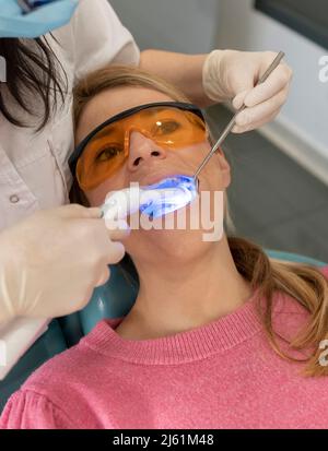 Zahnarzt Trocknen zahnärztliche Füllung mit Aushärtungslicht in der medizinischen Klinik Stockfoto