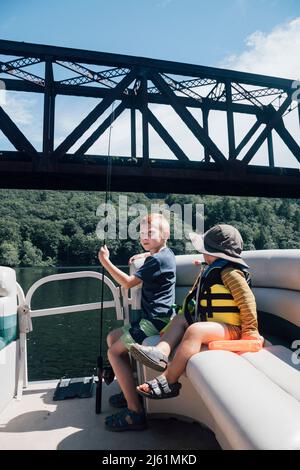 Jungs sitzen im Boot mit Angelrute an sonnigen Tag Stockfoto