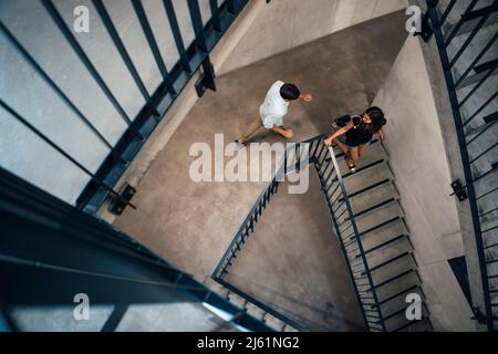 Junger Mann, der hinter der Freundin herläuft und die Stufen hinuntergeht Stockfoto