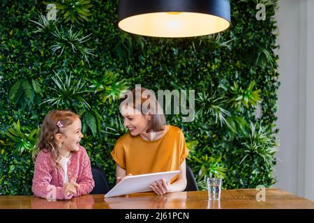 Lächelnde Mutter mit Tochter, die zu Hause einen Tablet-PC benutzt Stockfoto