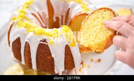 Schritt für Schritt. Schneiden von Zitronenbundtkuchen mit Zitronenschale auf einem Kuchenständer verziert. Stockfoto