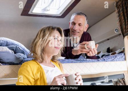 Mann, der eine nachdenkliche Frau mit einer Kaffeetasse im Wohnmobil ansieht Stockfoto