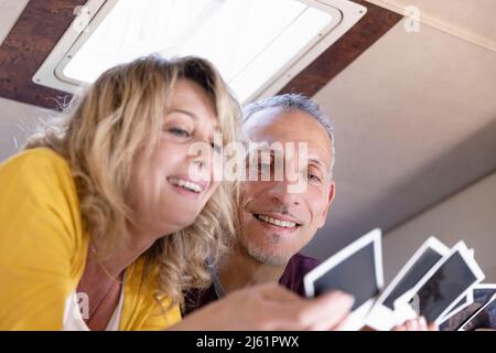 Lächelndes reifes Paar, das im Wohnmobil auf ein Foto schaut Stockfoto