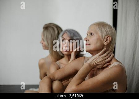 Besinnliche ältere Frau mit Freunden, die zu Hause sitzen Stockfoto