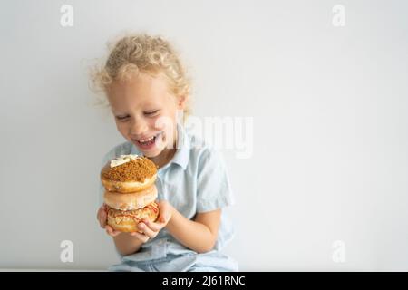 Glückliches Mädchen hält Stapel von Donuts Stockfoto
