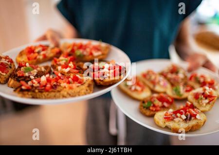 Mädchen serviert frische Bruschetta auf den Tellern Stockfoto