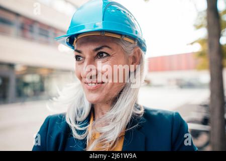 Lächelnder Ingenieur mit Hardhut im Büropark Stockfoto