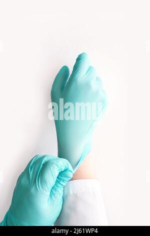 Medizinischen Handschuh anziehen. Chirurgie Arzt Hand. Medizinische Operationsgeräte für das Gesundheitswesen. Fachkundige Reinigung des Krankenhausarms. Geste zum Schutz der Hygiene. Steriles Hygienekonzept. Grüne Farbe Stockfoto