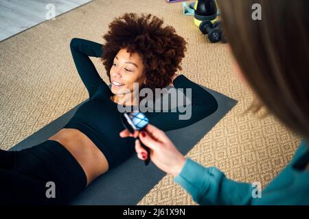 Lächelnde junge Frau mit den Händen hinter dem Kopf, die zu Hause arbeitet Stockfoto