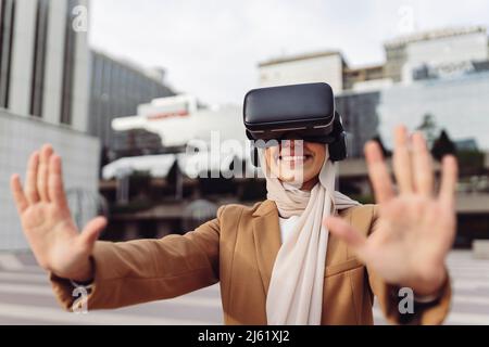 Glückliche Geschäftsfrau trägt virtuelle Realität Simulator gestikuliert Stop-Zeichen Stockfoto