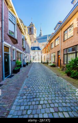 Niederlande, Südholland, Leiden, leere Kopfsteinpflaster-Gasse mit Kirche im Hintergrund Stockfoto