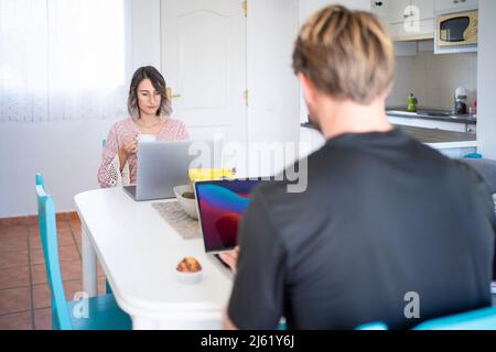 Freiberufler, die an Laptops arbeiten, die am Esstisch sitzen Stockfoto