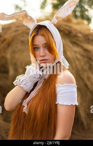 Junge Frau mit Hasenkostüm-Ohren vor Heuballen Stockfoto