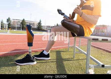 Mann mit einer laufenden Beinprothese auf der Bank sitzend Stockfoto