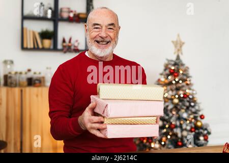 Glücklicher älterer Mann, der Geschenkboxen zu Hause hält Stockfoto