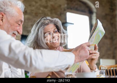 Glückliches Seniorenpaar, das den Stadtplan im Boutique-Hotel teilt Stockfoto