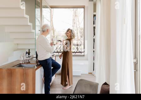 Senior-Paar toasten Weingläser in der Küche im Hotel-Apartment Stockfoto